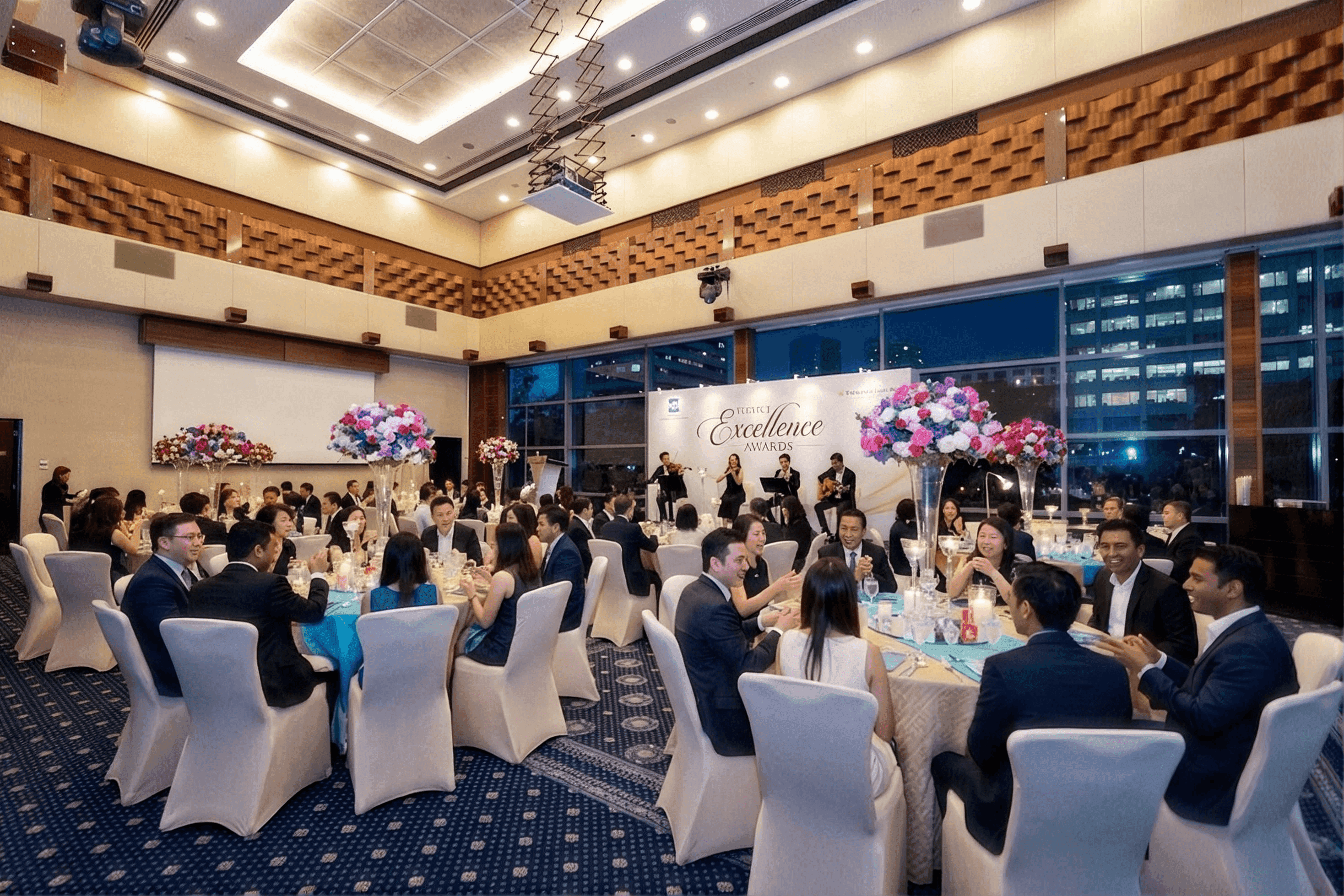 Guests in formal attire attend an elegant corporate dinner with floral arrangements and city views.